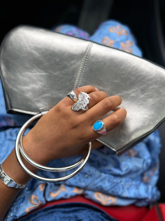 Hand wearing the Doomi Afrik 925 silver ring while holding a silver clutch.