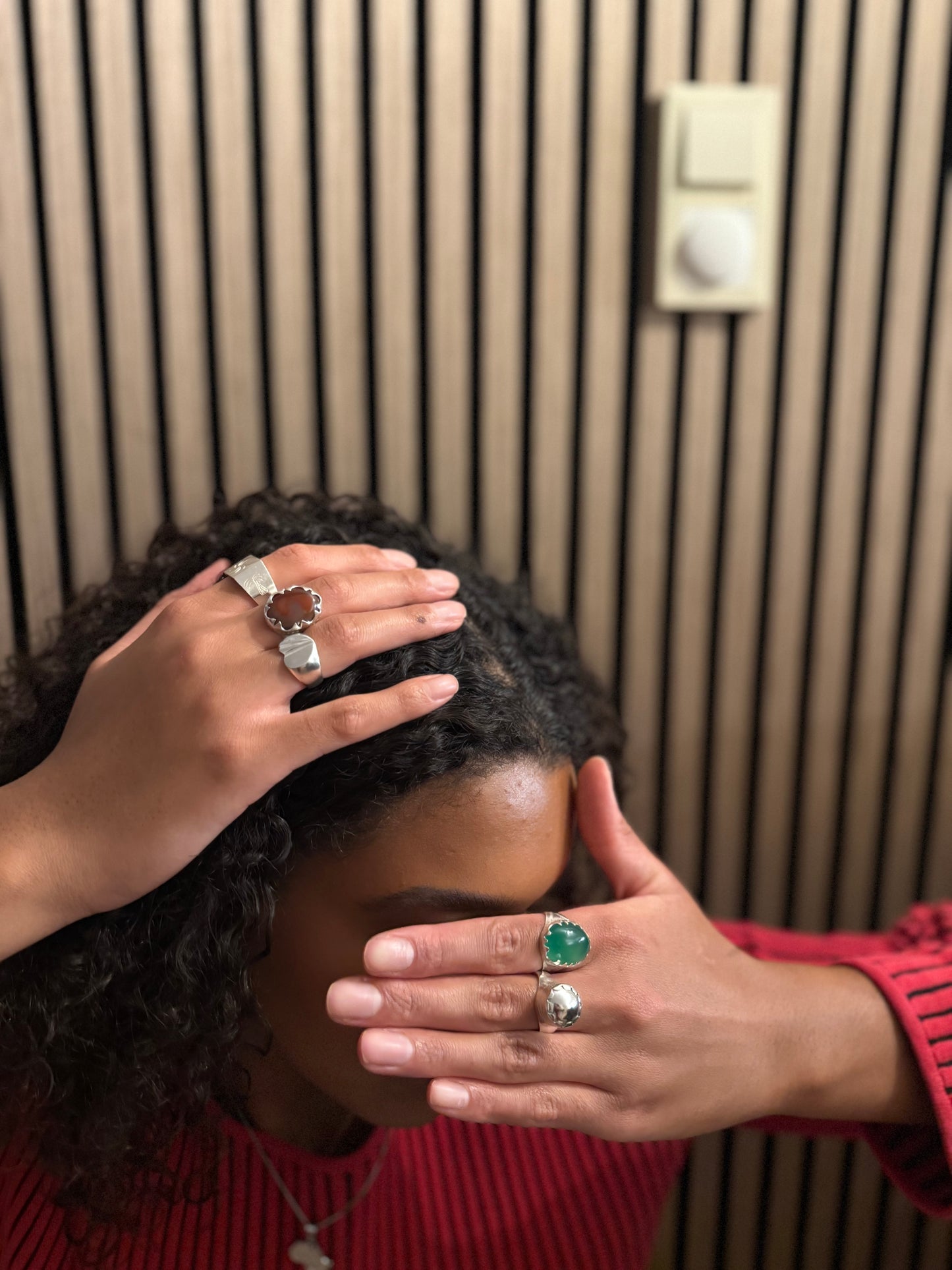 Person wearing multiple rings with gemstones against a neutral background