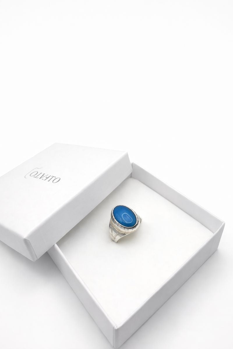 Silver ring with a blue stone in a white yafato box on a white background