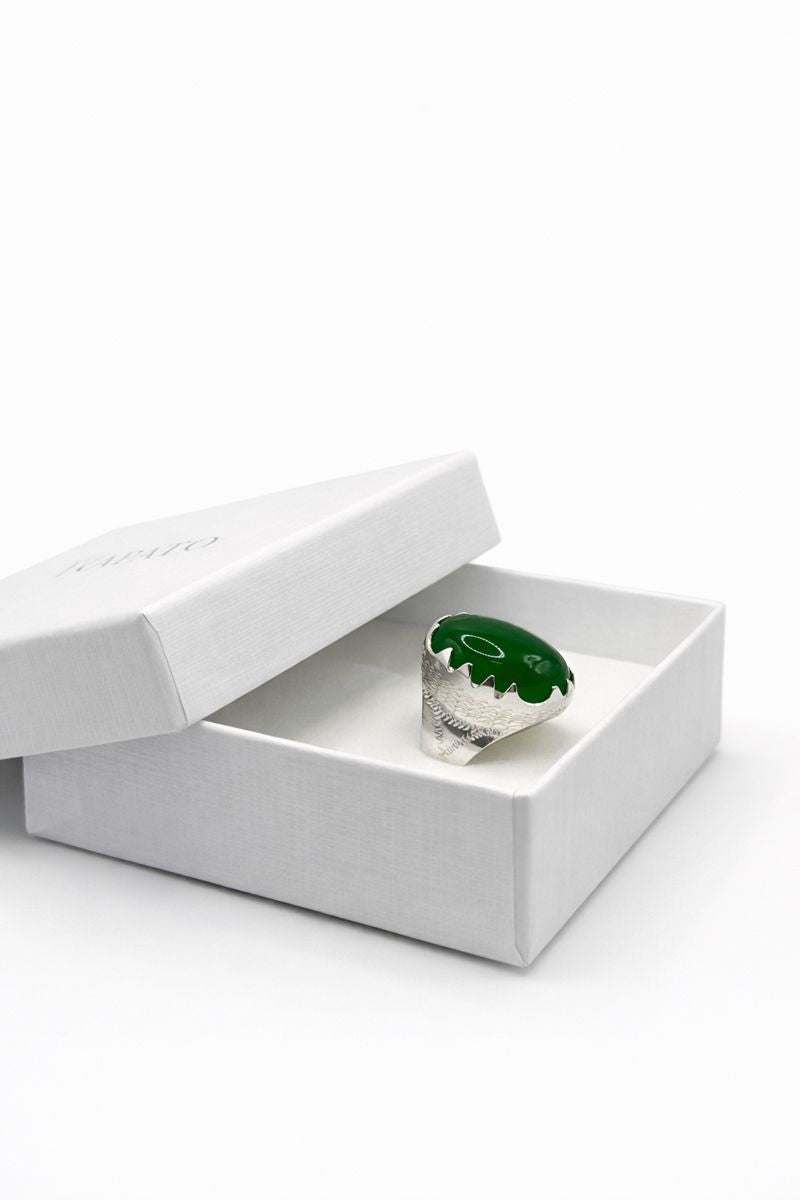 Green stone ring in a white box on a white background